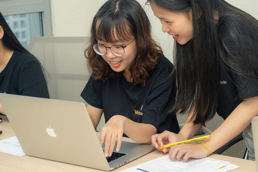 pexels-photo-2789242-2789242-1 Two women smiling and working together on a laptop, embodying teamwork and collaboration in an office.