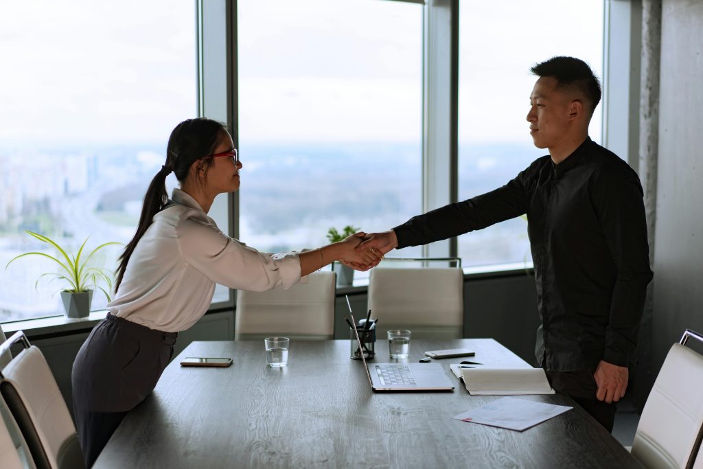 pexels-photo-8101767-8101767 Professional coworkers exchange a handshake in a modern corporate office setting.